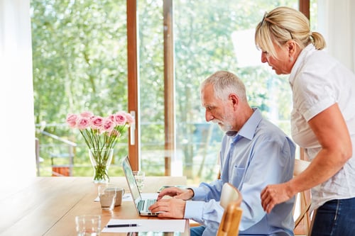 old man using a laptop and an old woman looking at the laptop