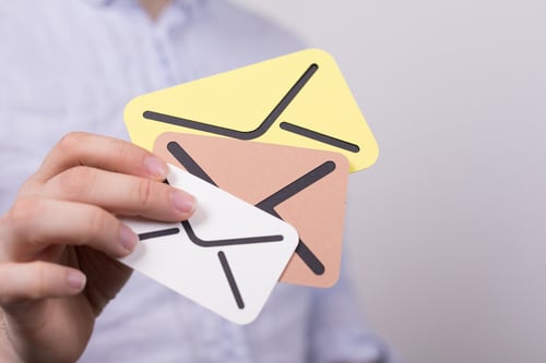 Person holds three small cutouts of envelope illustrations