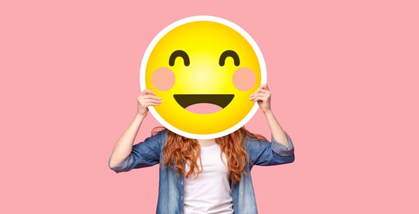 Redhead girl hiding her face behind happy emoji smile