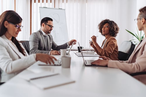 four people working and sitting together in one table