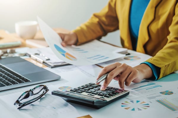Nonprofit budget template: woman working on finance in front of a laptop with calculator
