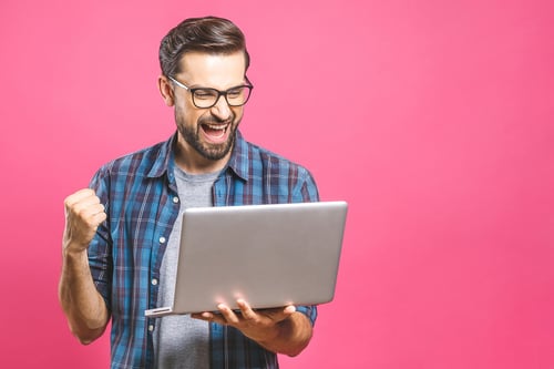 Happy man holding laptop and celebrating his success