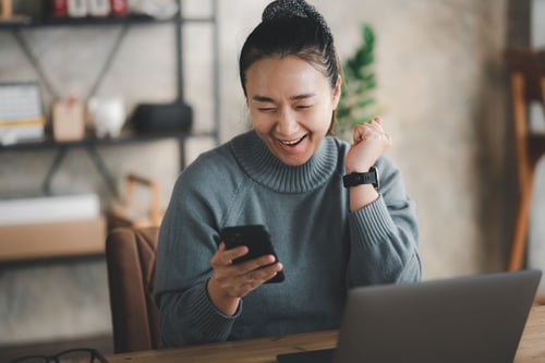 woman smiling while looking at her phone