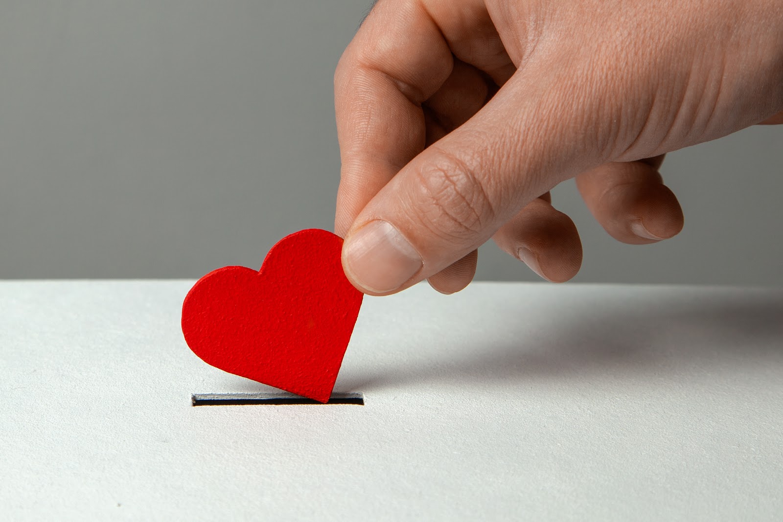 A man dropping a cut out of a red heart into a box